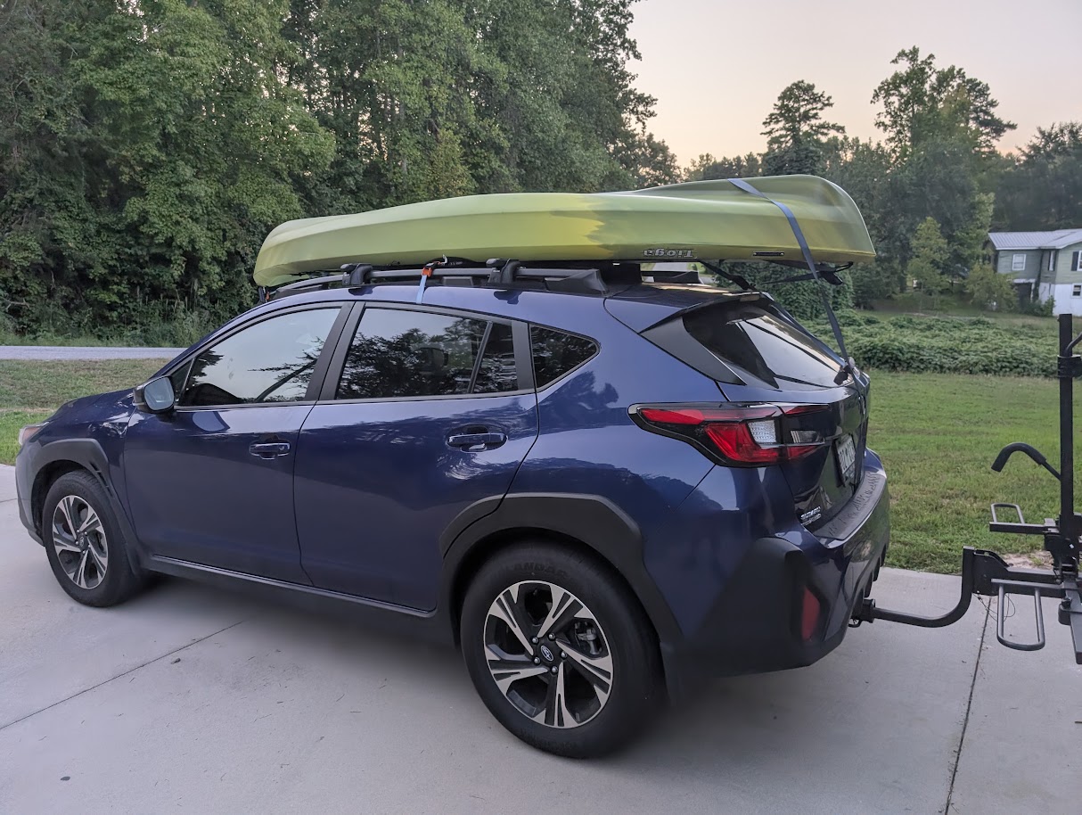 A green kayak secured to the roof rack of a blue SUV.