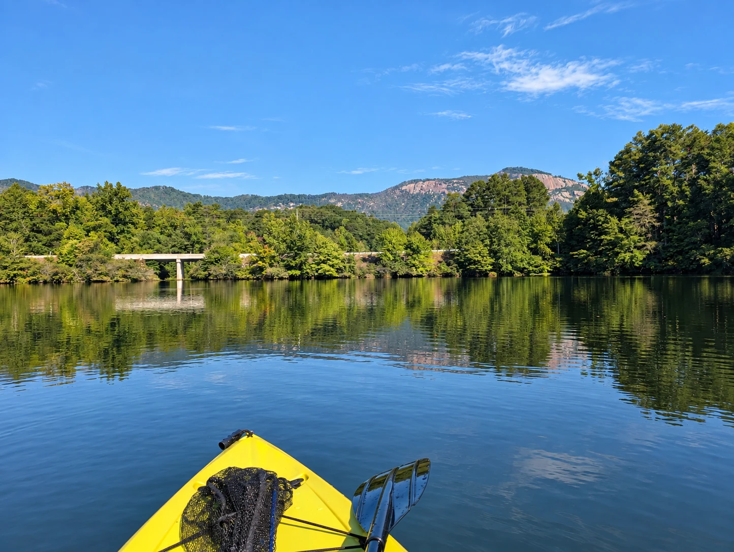 Table Rock beyond a tree-lined shore, reflected in the water ahead of a yellow kayak